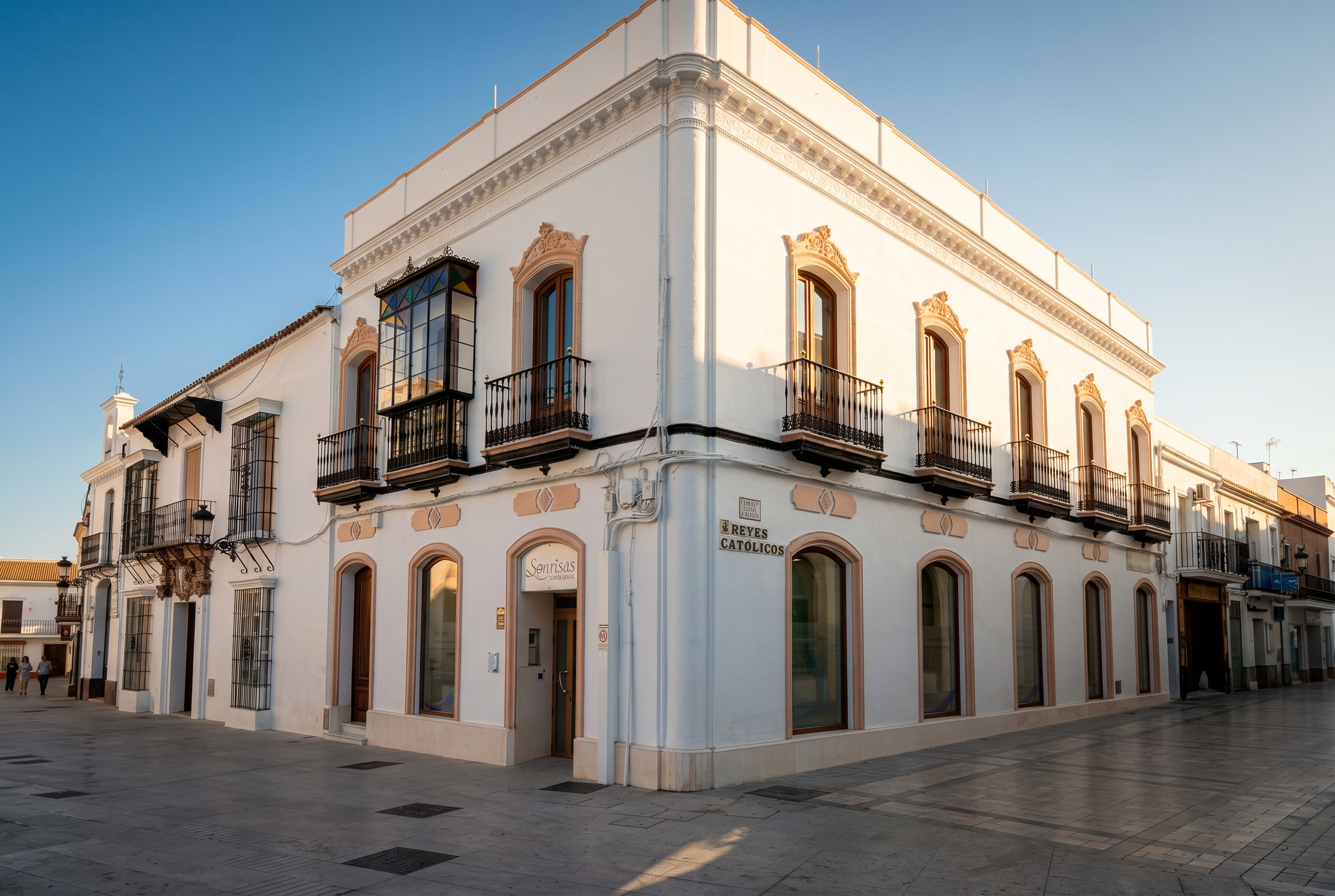Fachada de la Clínica Dental Sonrisas al atardecer, en la esquina de la calle Reyes Católicos, Moguer